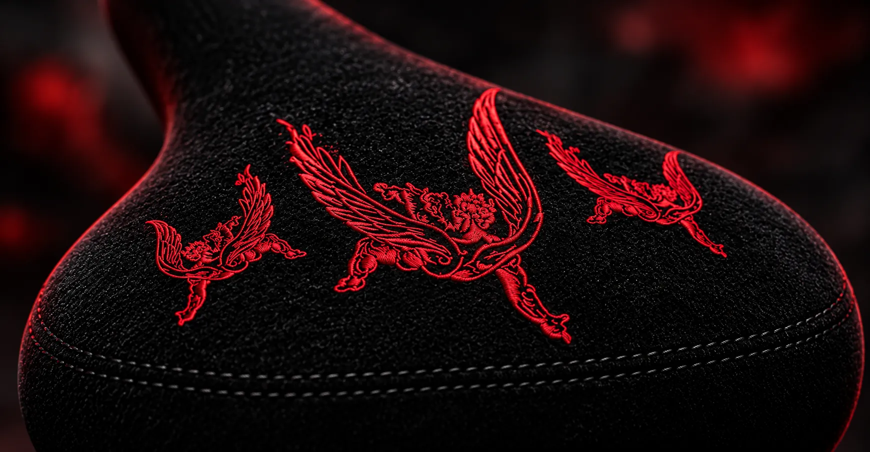 Close-up ilustrativo da parte traseira do banco Anjos Caídos, com três anjos bordados em vermelho